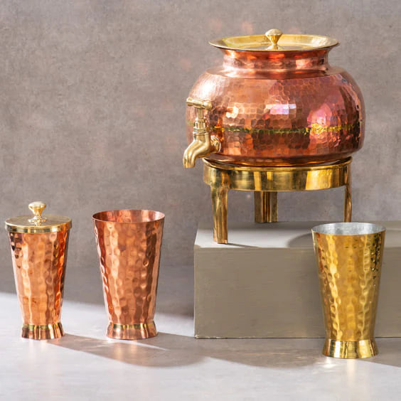Decorative hammered copper and brass beverage dispenser with matching cups, perfect for serving drinks.