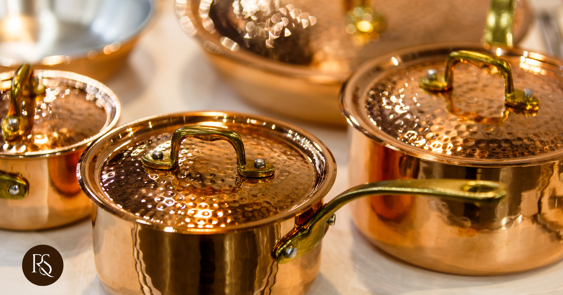 a collection of hammered copper cookware with gold handles, showcasing elegance and craftsmanship in kitchen essentials